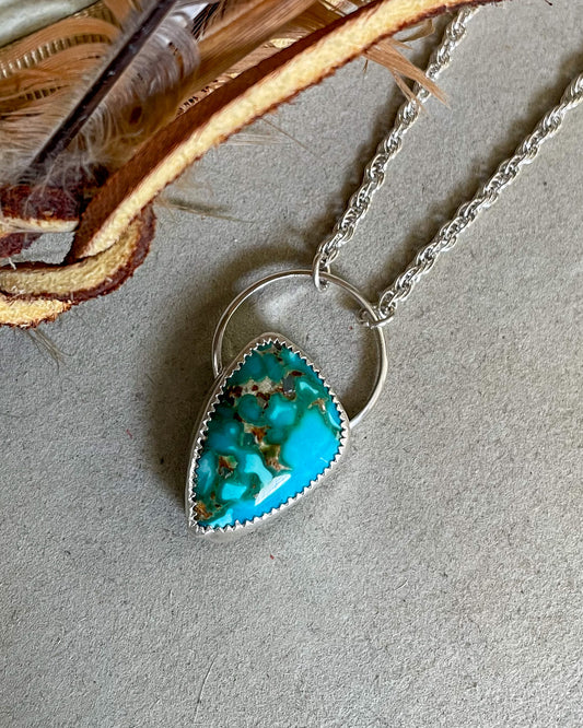 handcrafted blue and green kingman turquoise in unique asymmetrical shape hung from an oversized full circle bail and a french rope chain.