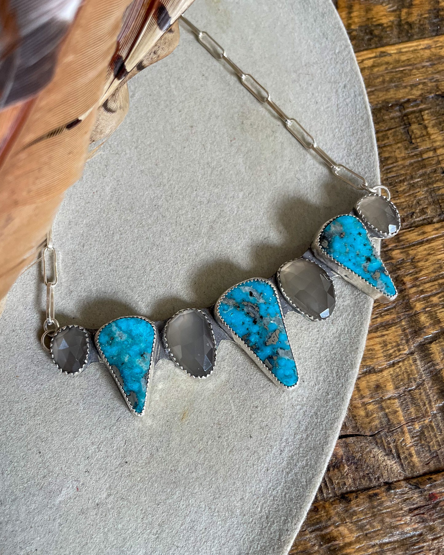 handcrafted chest collar necklace with alternating grey moonstone and triangular ithica peak turquoise pointing down. silver paperclip chain attaches at each end