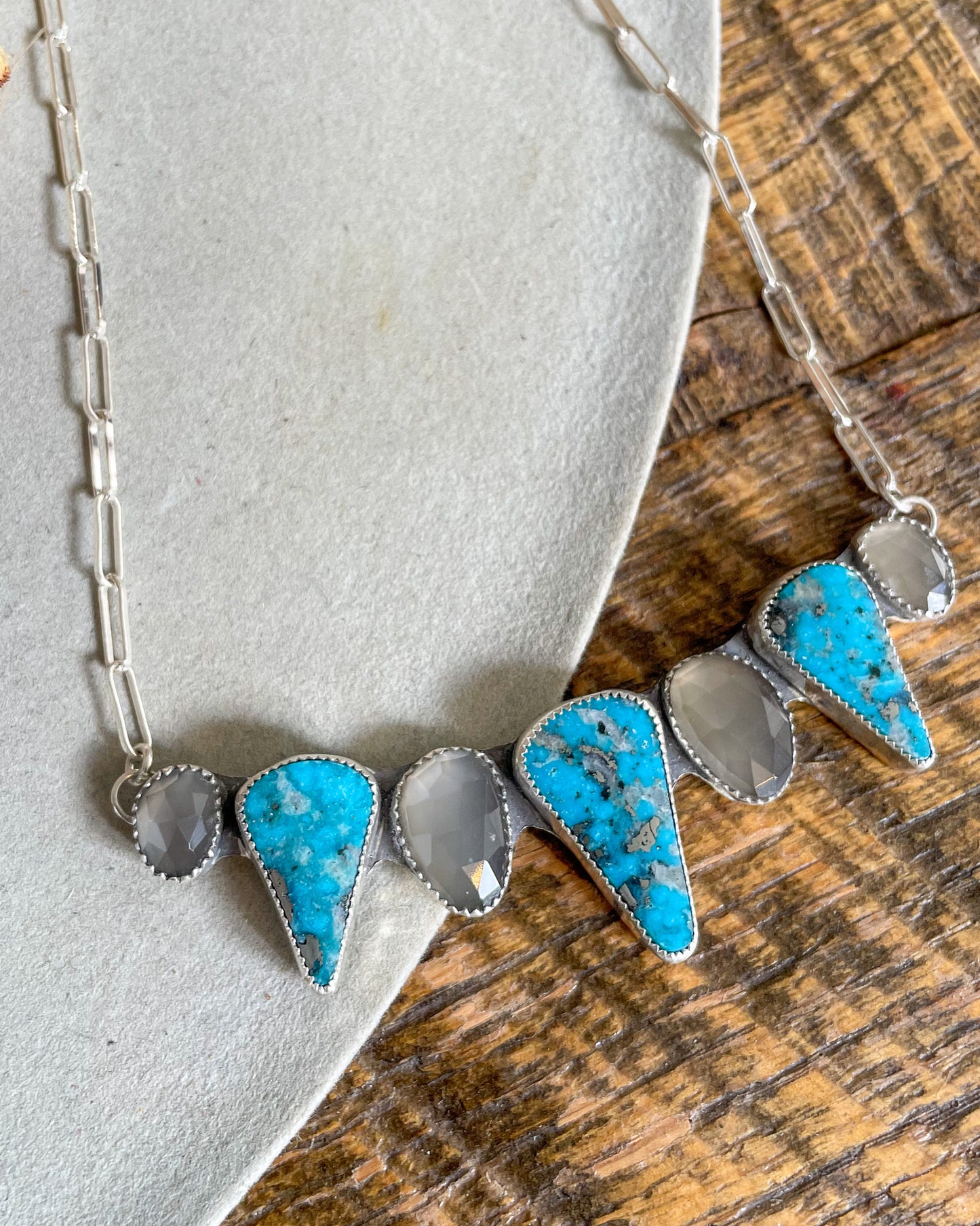 handcrafted chest collar necklace with alternating grey moonstone and triangular ithica peak turquoise pointing down. silver paperclip chain attaches at each end