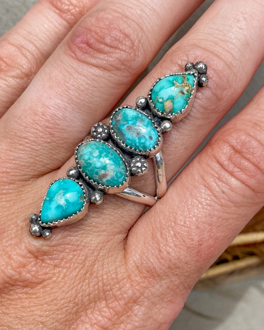 handcrafted sterling silver ring with four stacked turquoise stones in white water and emerald valley turquiose with floraal and hand forged silver accent beads on a split shank