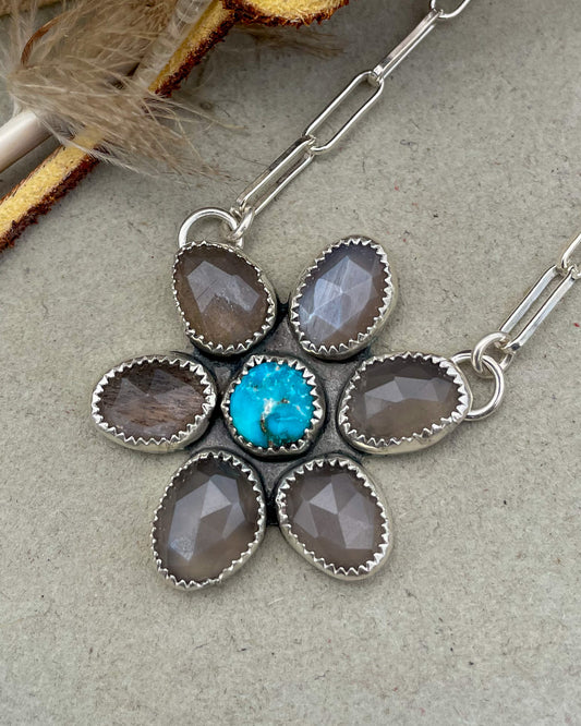 handcrafted flower pendant with center turquoise cabochon and six grey moonstone rosecut pedals attached by jump rings on two pedals to paperclip chain