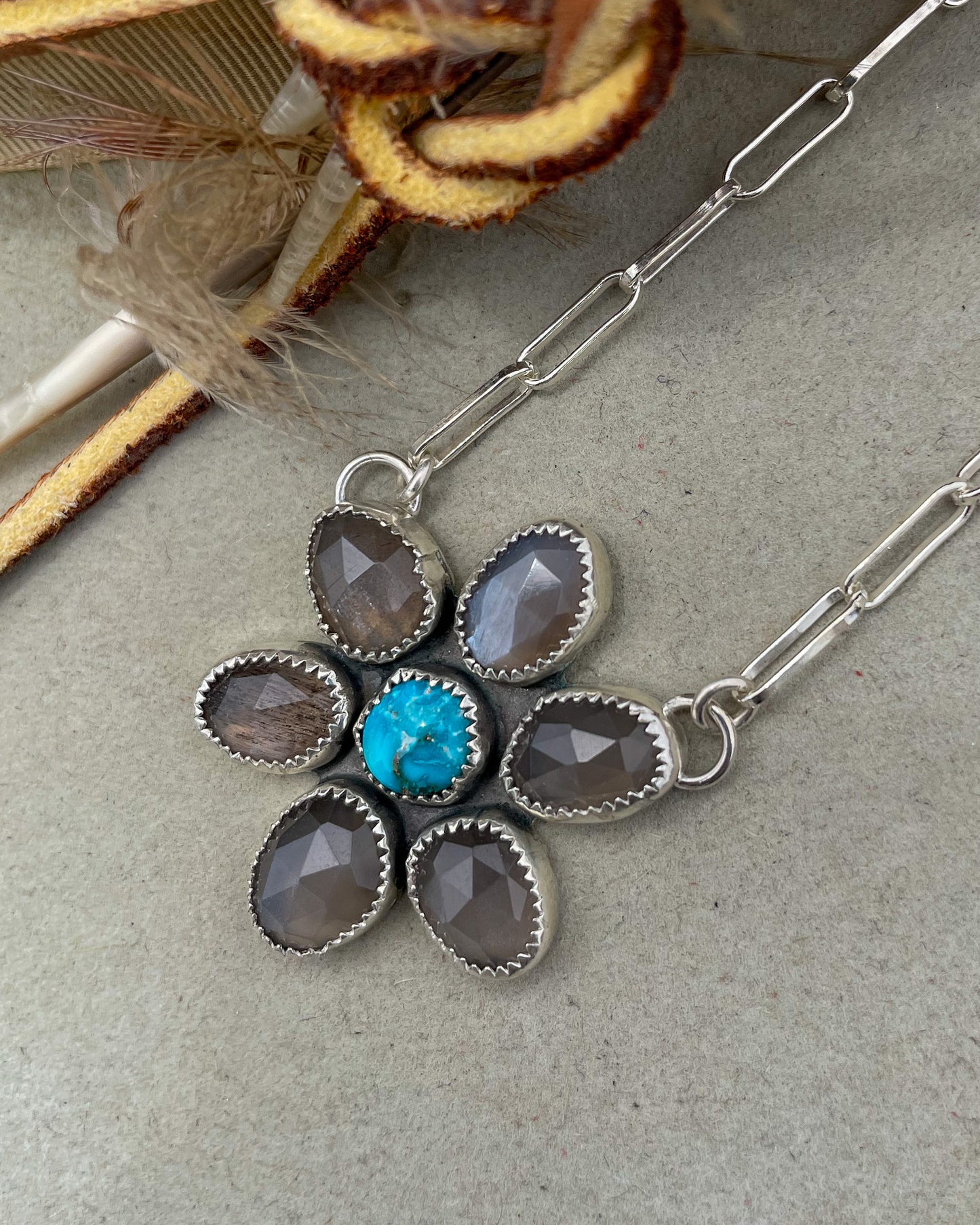 handcrafted flower pendant with center turquoise cabochon and six grey moonstone rosecut pedals attached by jump rings on two pedals to paperclip chain