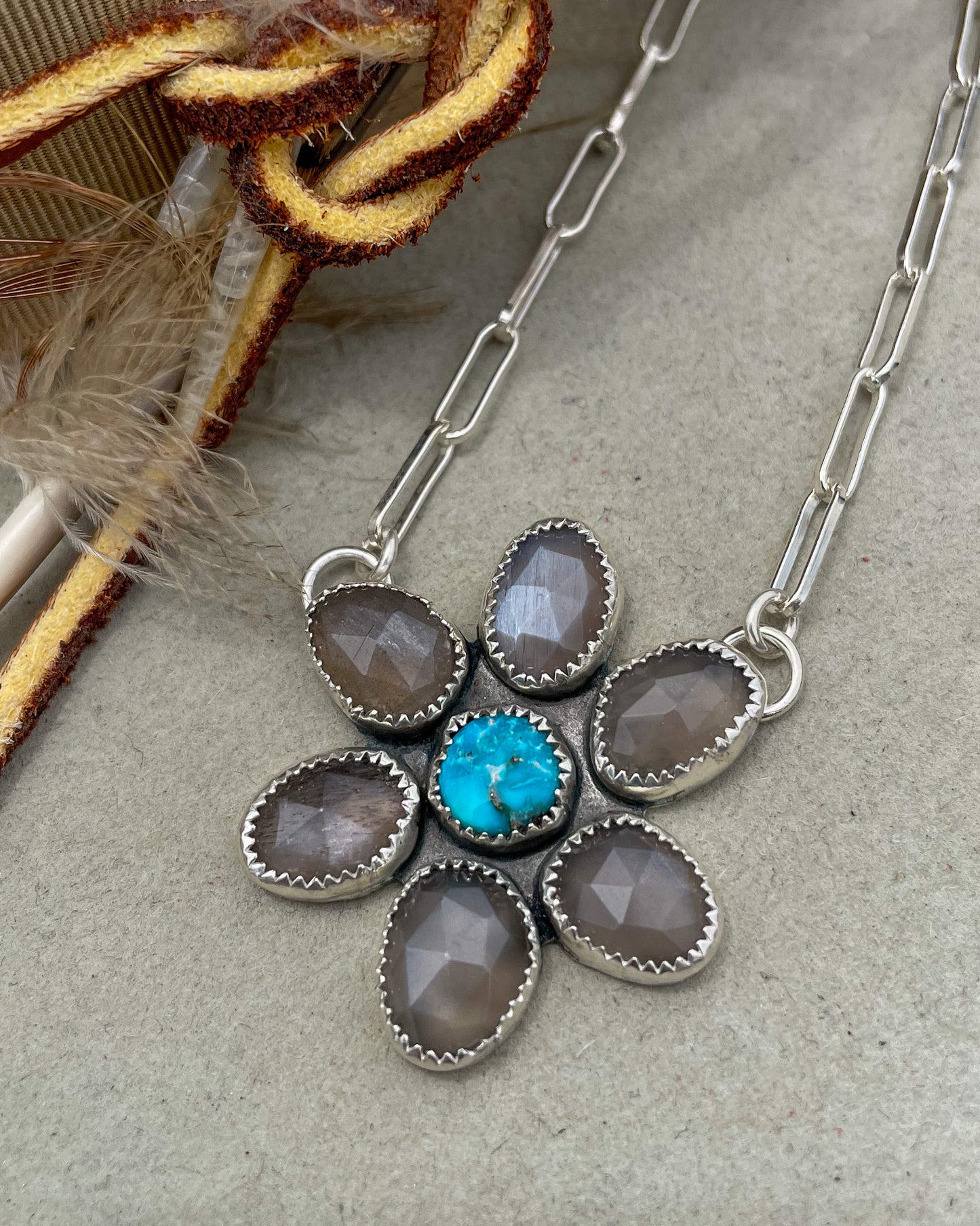 handcrafted flower pendant with center turquoise cabochon and six grey moonstone rosecut pedals attached by jump rings on two pedals to paperclip chain