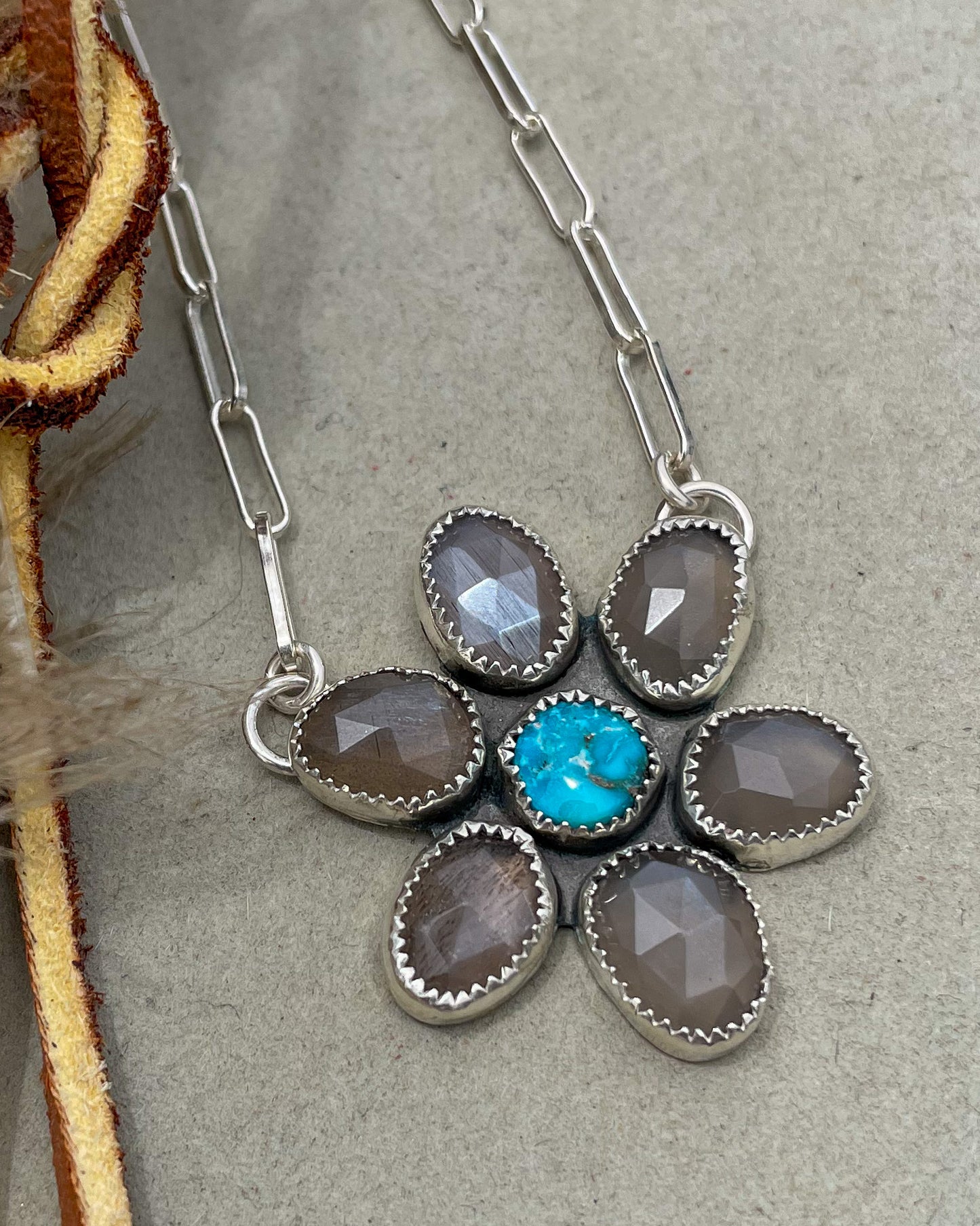 handcrafted flower pendant with center turquoise cabochon and six grey moonstone rosecut pedals attached by jump rings on two pedals to paperclip chain
