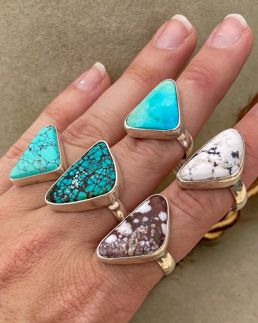 five turquoise triangular stone rings in smooth bezels on chunky silver bands