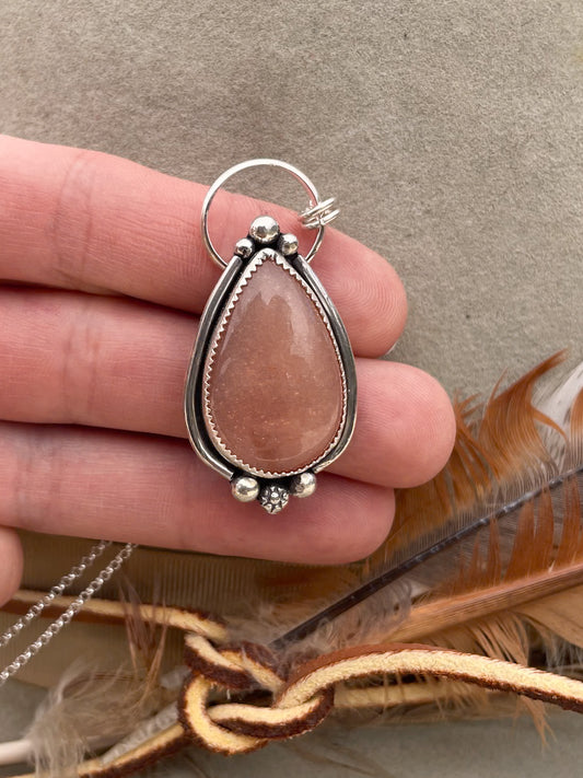 peach moonstone teardrop pendant with silver border and silver bead accents on dainty rolo chain