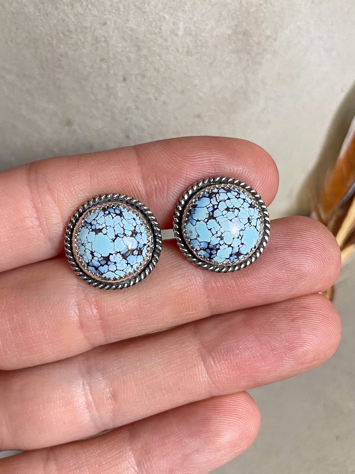 Pair of cufflinks with round golden hills turquoise turquoise stones and delicate rope border held in hand