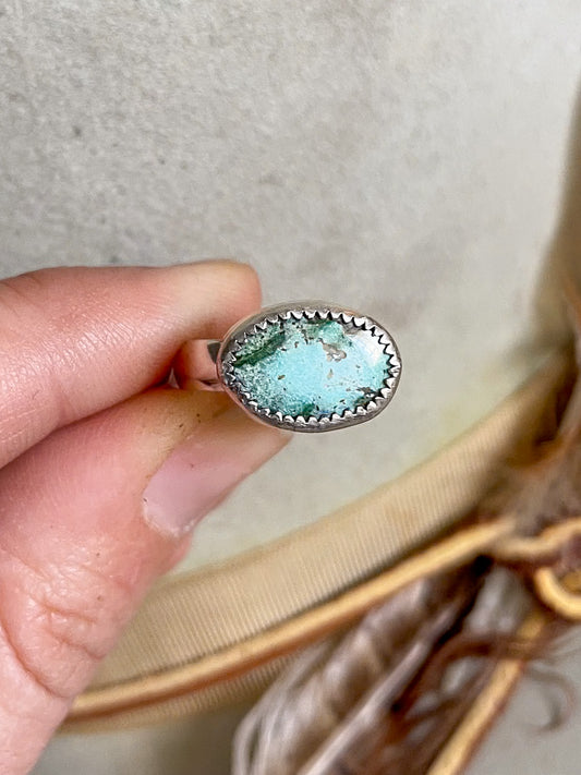 soft blue and rich green oval turquoise set horizontally on ring held in hand