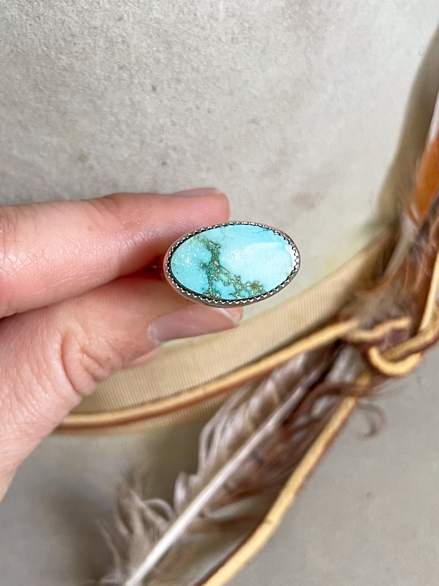 soft blue and rich green oval turquoise set horizontally on ring held in hand