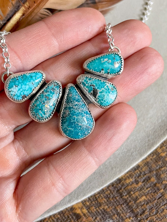 half cluster white water turquoise with five stones on rolo chain held in hand