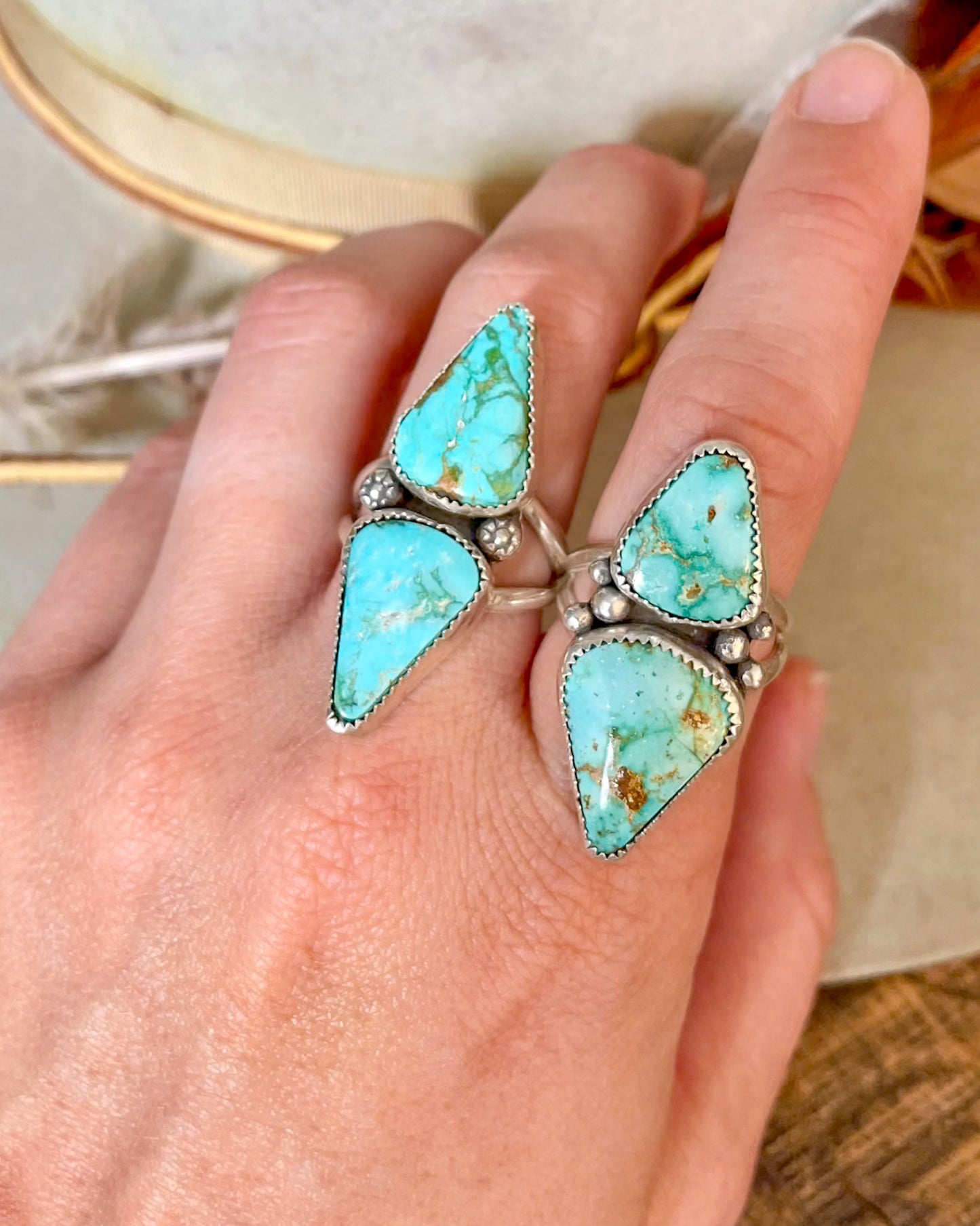 Two Turquoise Mountain double stone rings on a hand