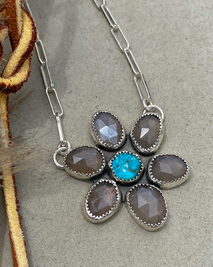 handcrafted flower pendant with center turquoise cabochon and six grey moonstone rosecut pedals attached by jump rings on two pedals to paperclip chain
