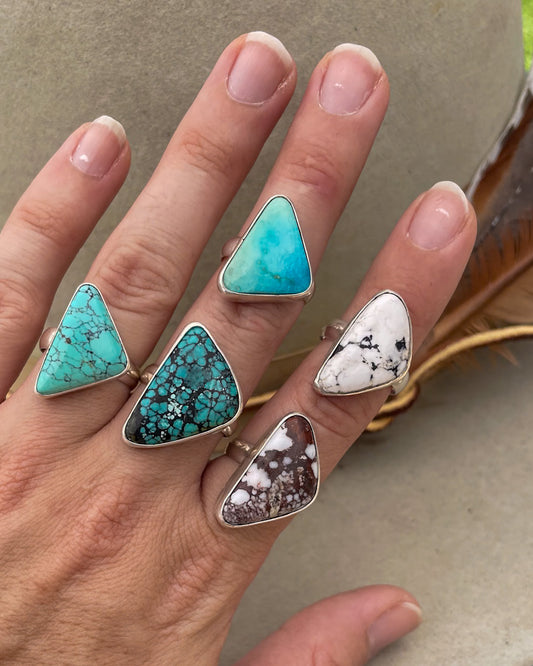 five turquoise triangular stone rings in smooth bezels on chunky silver bands