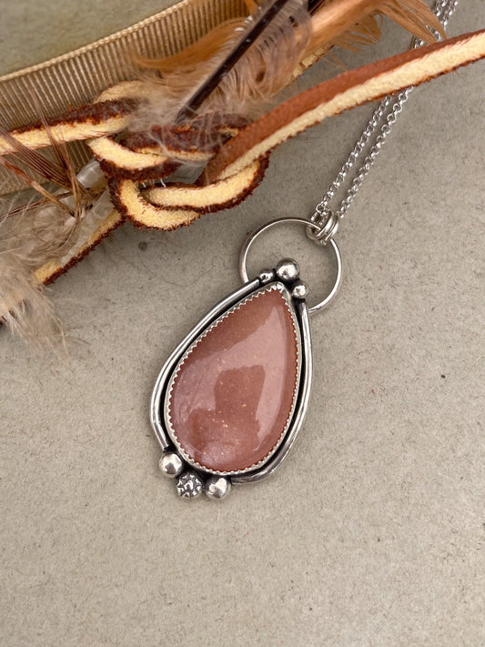 peach moonstone teardrop pendant with silver border and silver bead accents on dainty rolo chain