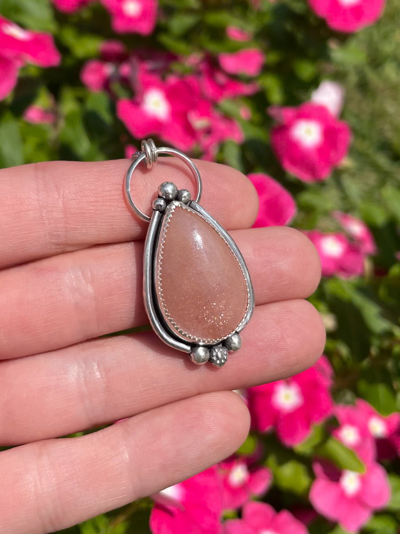 peach moonstone teardrop pendant with silver border and silver bead accents on dainty rolo chain
