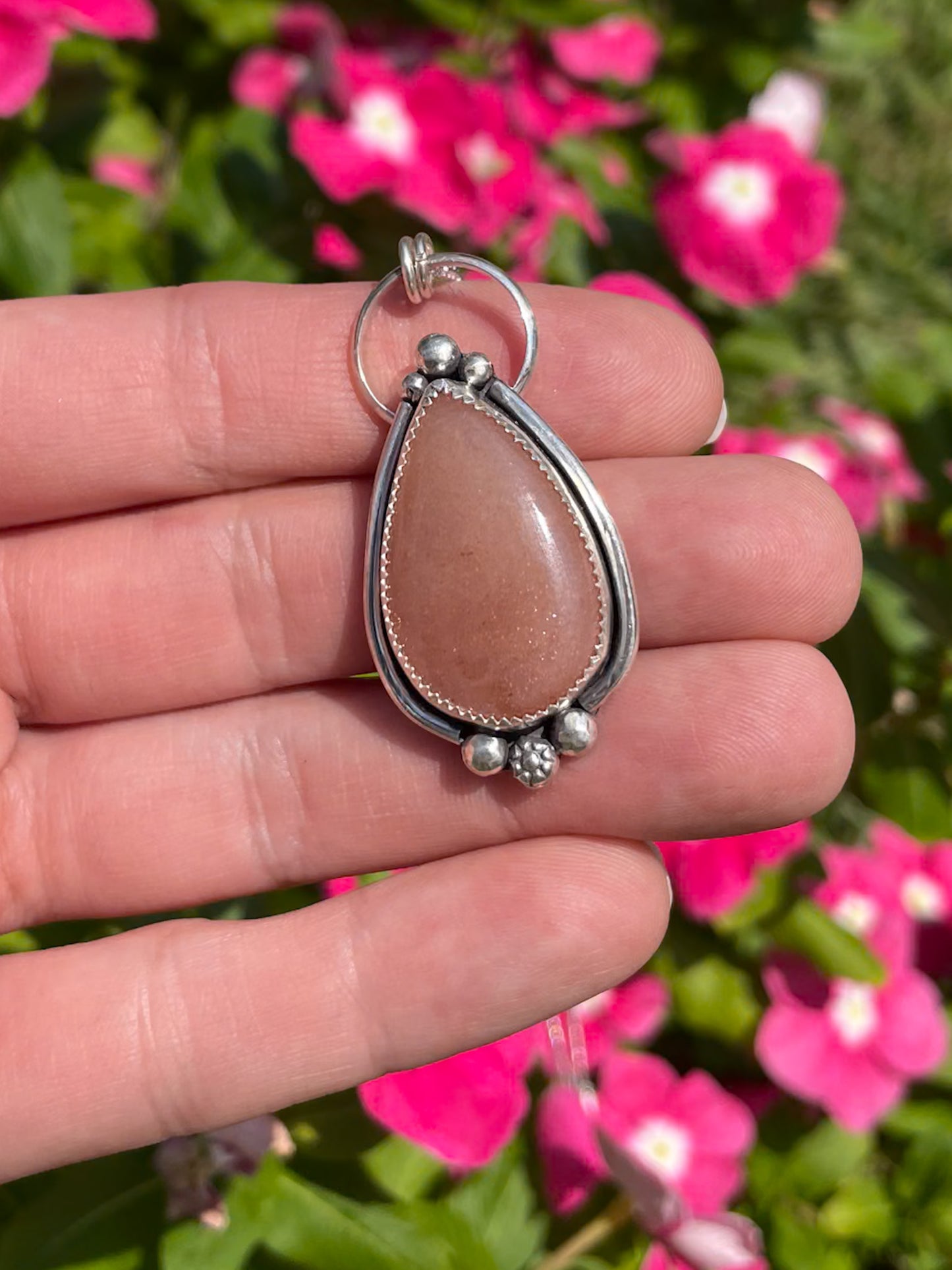peach moonstone teardrop pendant with silver border and silver bead accents on dainty rolo chain