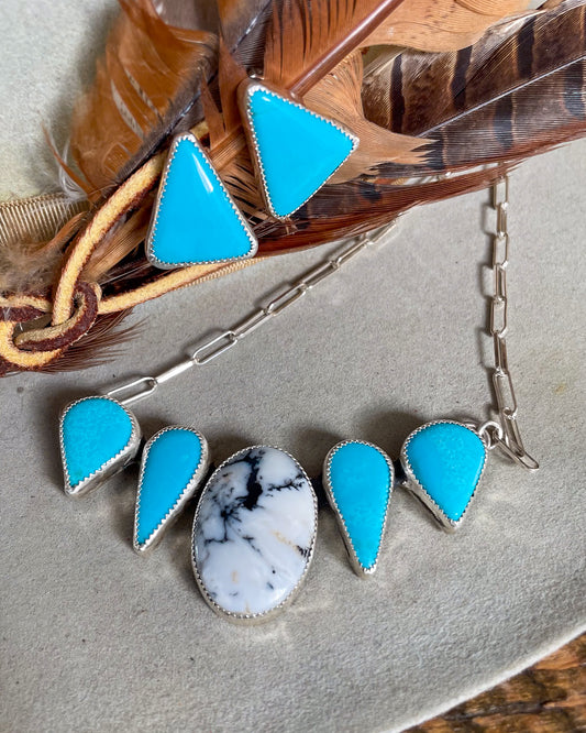 triangular sleeping beauty turquoise stud earrings on brown feather with matching white buffalo and sleeping beauty turquoise necklace