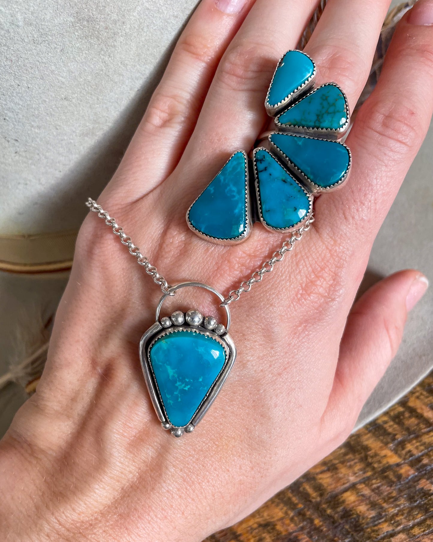 Peacock blue turquoise pendant on chunky silver rolo chain with matching  five stone half cluster ring on hand