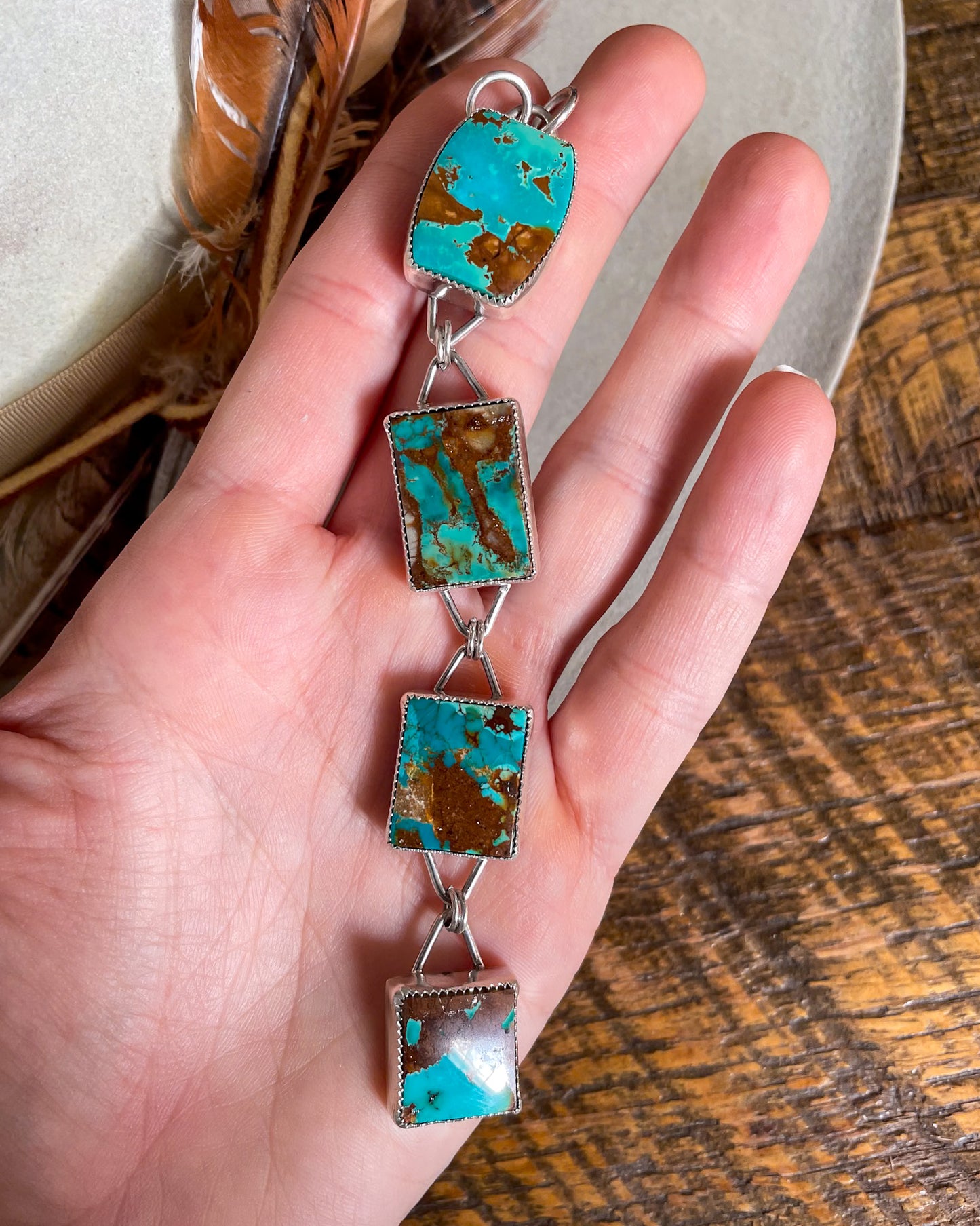 four stone pilot mountain turquoise pendant with rectangular stones connected in a row held in hand