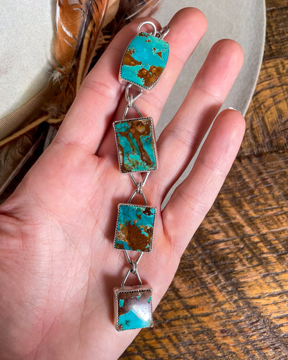 four stone pilot mountain turquoise pendant with rectangular stones connected in a row held in hand
