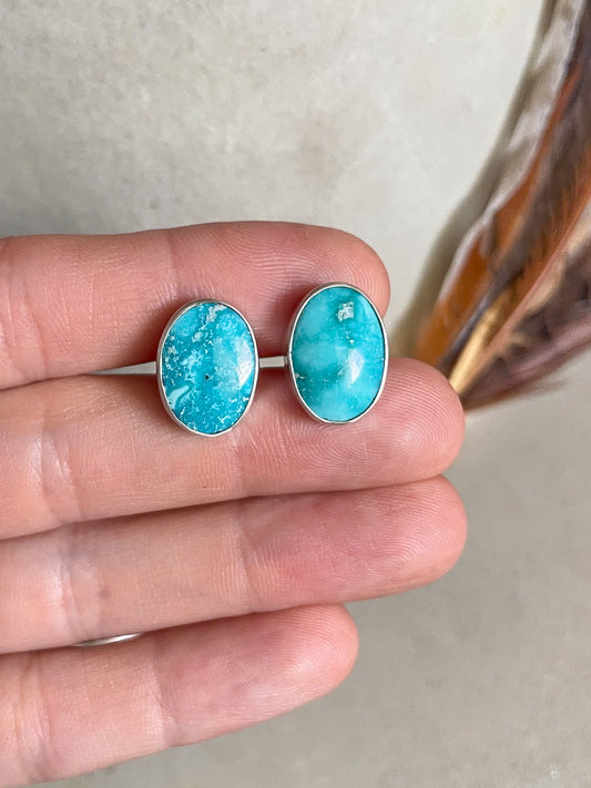 white water turquoise oval cufflinks held in hand