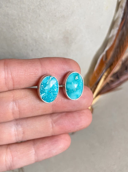 white water turquoise oval cufflinks held in hand
