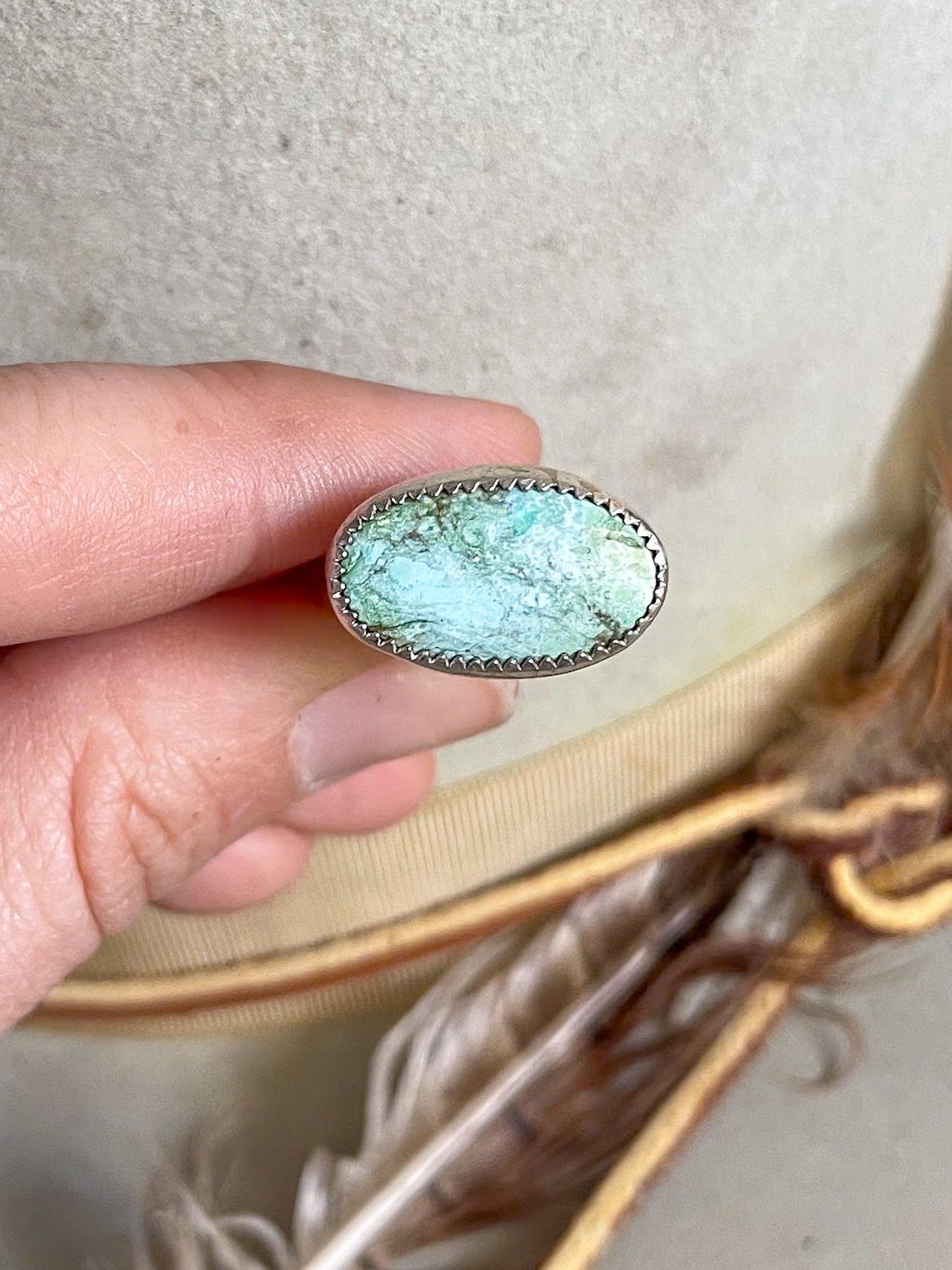 soft blue and rich green oval turquoise set horizontally on ring held in hand