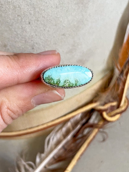 soft blue and rich green oval turquoise set horizontally on ring held in hand