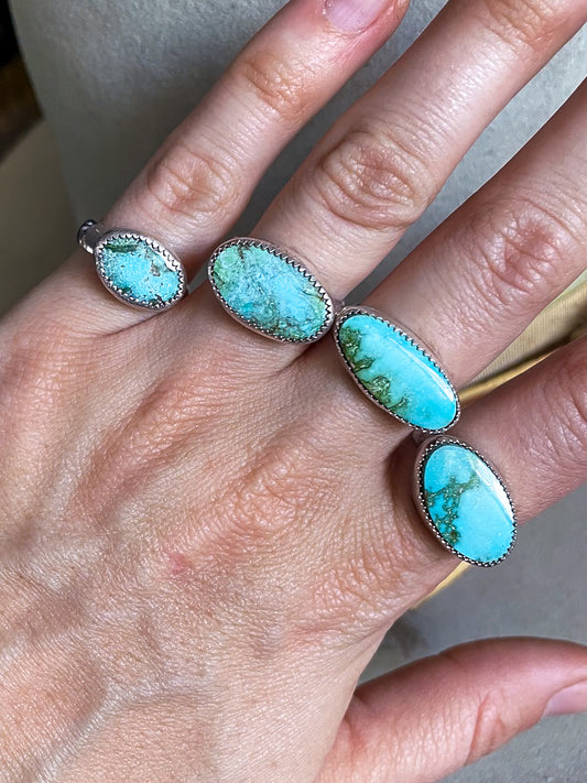 4 soft blue and rich green oval turquoise set horizontally on rings modeled on hand