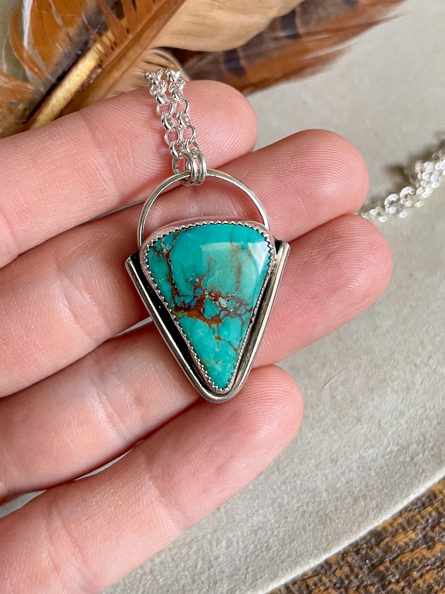 turquoise mountain pendant on rolo chain held in hand