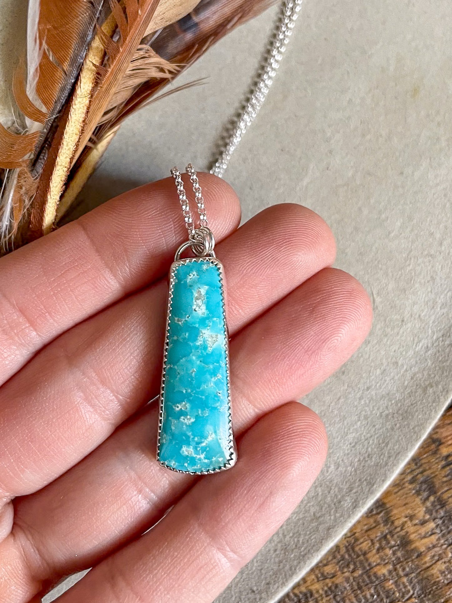 long gobi turquoise pendant on dainty chain held in hand