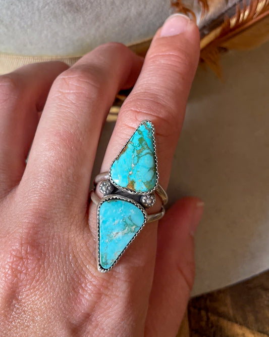 mirrored turquoise mountain turquoise cabochons seperated by floral accents on split shank band worn on finger