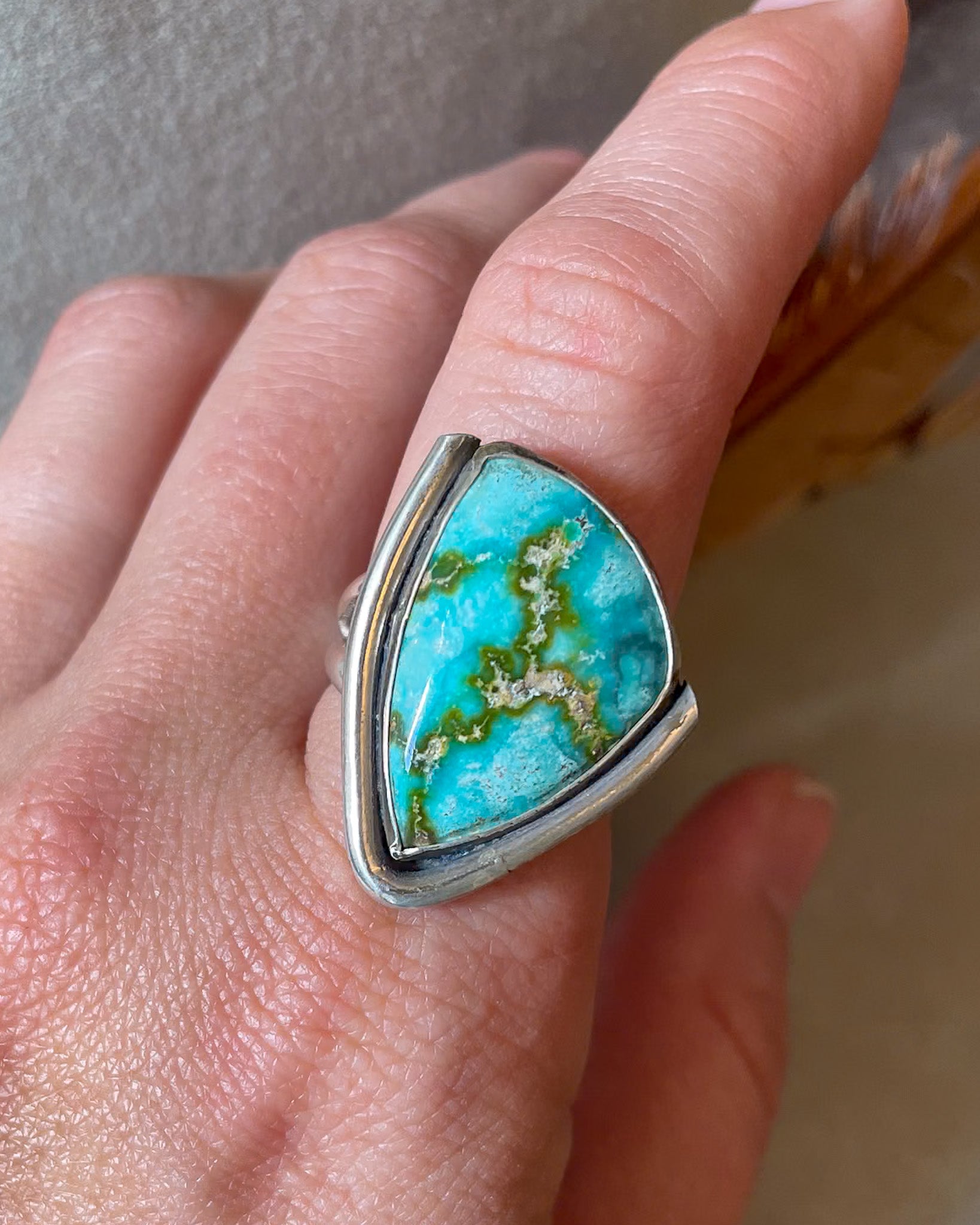 asymmetrical sonoran gold turquoise ring with border modeled on hand