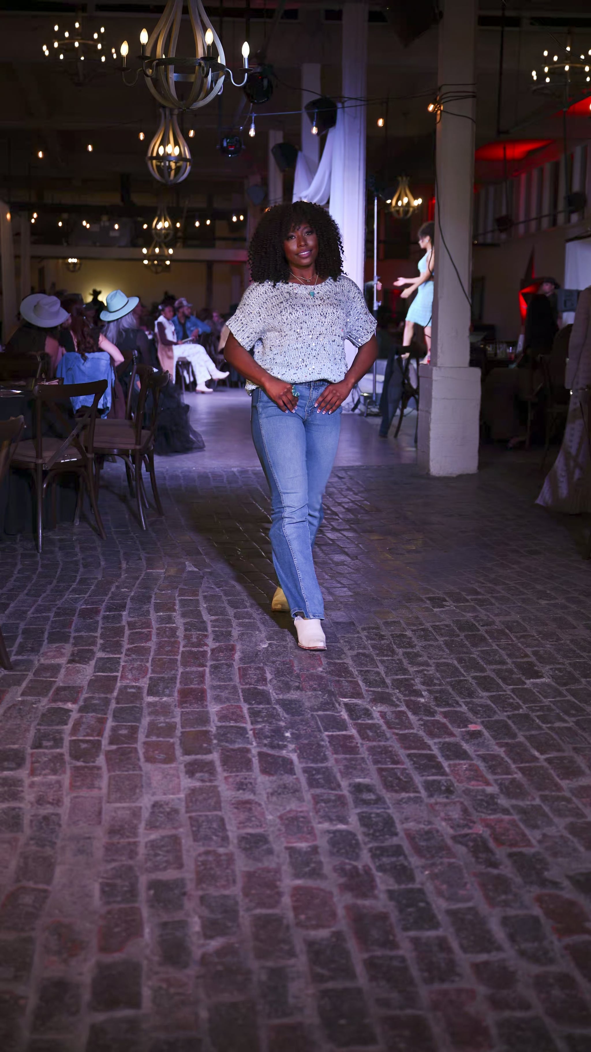 woman wearing peacock blue turquoise ring and necklace with sequin top walking on fashion show runway