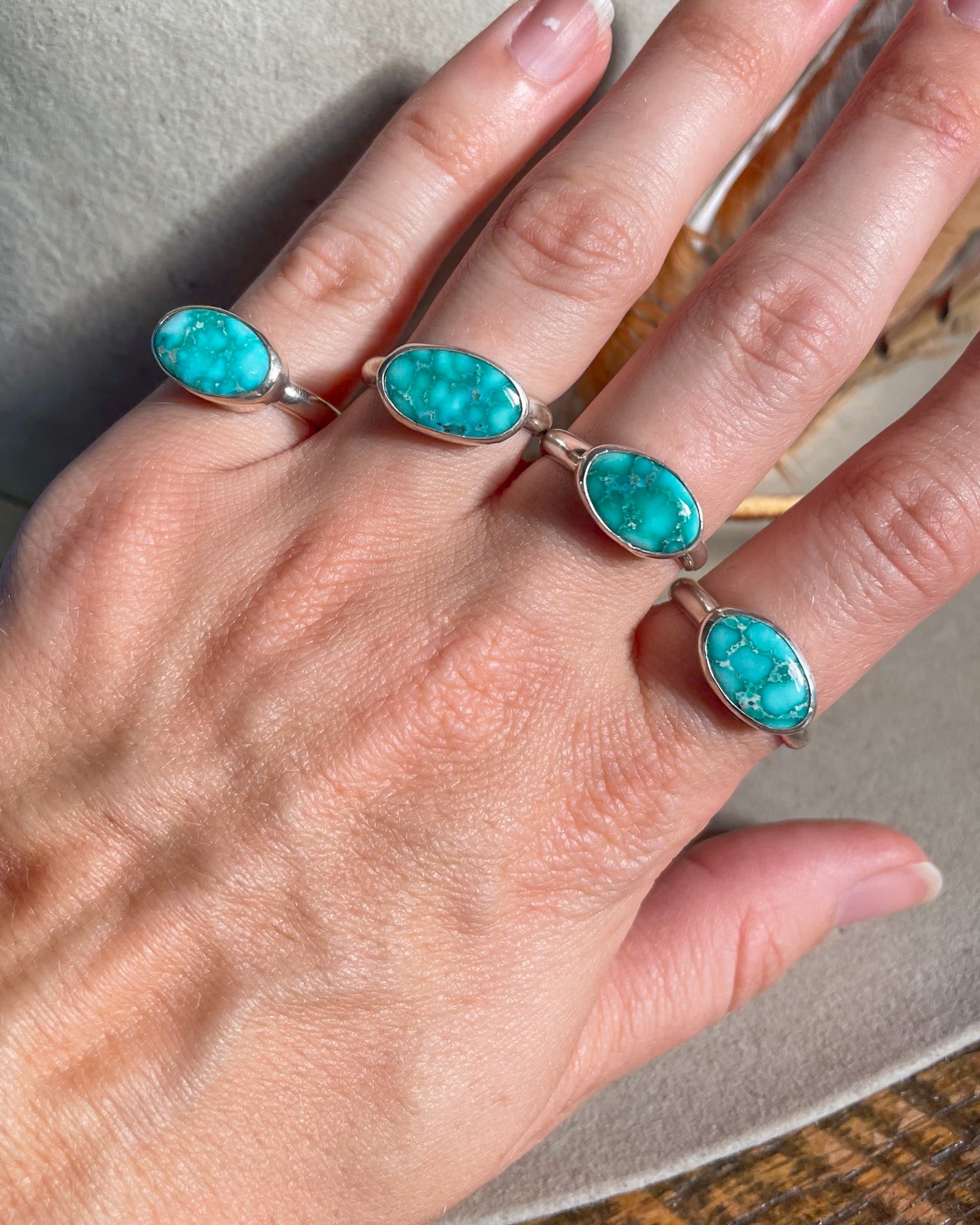 four east west turquoise stone rings modeled on hand