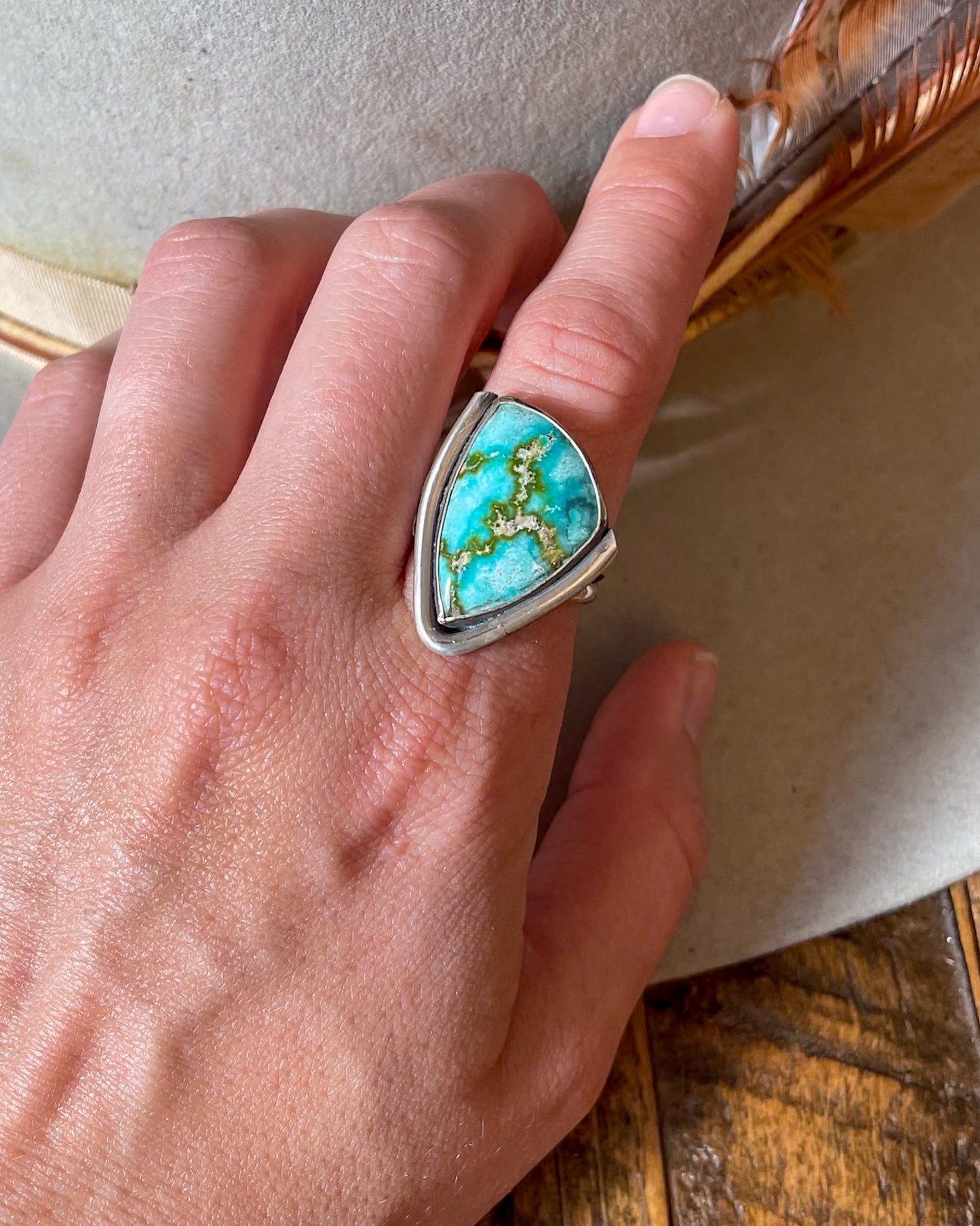 sonoran gold triangular ring with smooth border on two sides modeled on hand